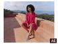 Eine Frau in einem rosa ESMARA® Damen Tunika-Kleid sitzt auf einer Terrasse. [KI-generiertes Bild]