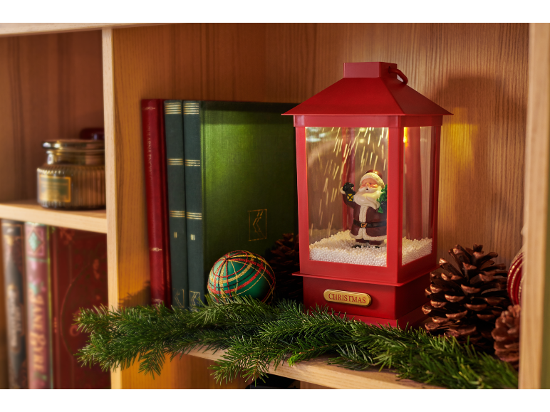 Weihnachtslaterne mit Weihnachtsmannfigur, Büchern und Tannengirlande auf einem Holzregal.
