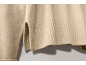 Detail des Rippbündchens und des Seitenschlitzes eines beigen Strickpullovers.