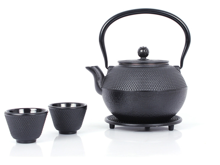 Eine schwarze Gusseisen-Teekanne mit zwei Tassen.