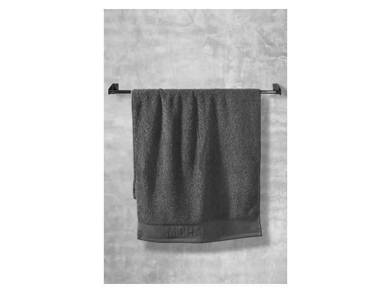 Ein graues Handtuch von Michael Kors hängt an einem Handtuchhalter.