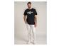 Mann in schwarzem T-Shirt mit dem Text „NAJLEPSZY TOP DAD“ und weißer Hose.