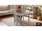 Junge zeichnet an einem Kindertisch mit Stuhl in einem Zimmer mit Bett und Spielzeugregal.