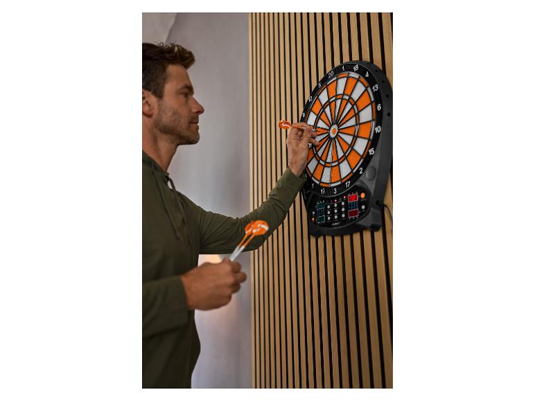 Mann spielt Dart auf einer elektronischen Dartscheibe mit orangefarbenen und weißen Segmenten.