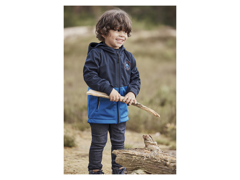 Ein Junge trägt eine blaue Softshelljacke mit Kapuze und dem Aufdruck 'Arctic Adventure'