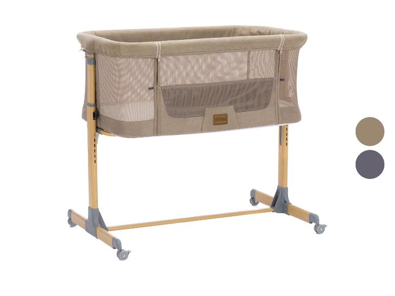 Fillikid Babybett in Beige mit Holzrahmen und Rollen.