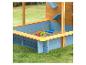 Holzsandkasten mit blauen und gelben Details, Sandspielzeug und Wasserrutschen.