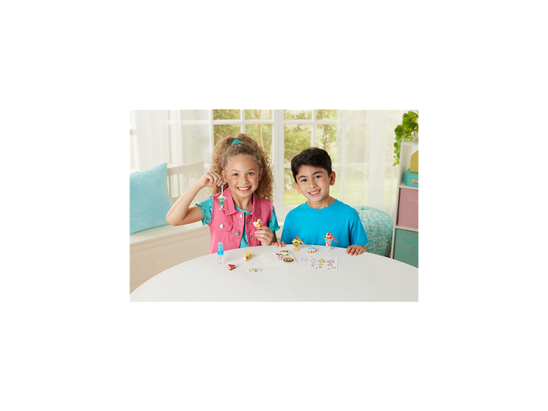 Zwei lächelnde Kinder halten Bastelkreationen von Miniaturdesserts und Lebensmitteln.