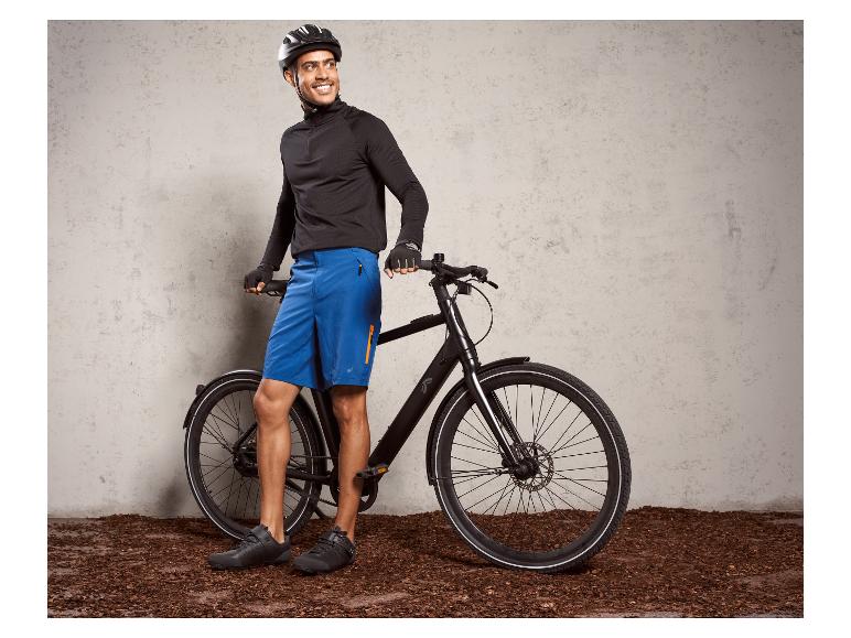 Ein Mann in Fahrradkleidung lehnt sich an ein schwarzes E-Bike.