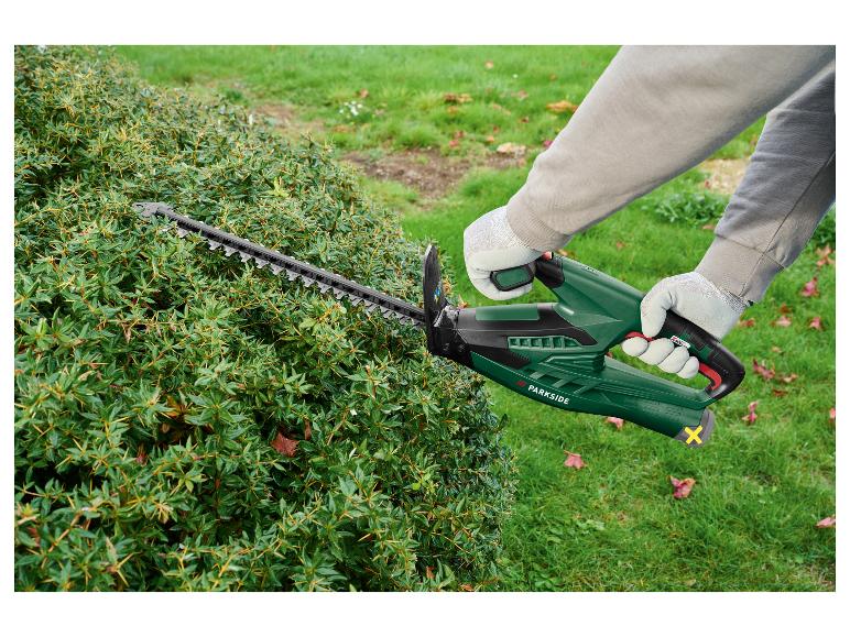 Person schneidet einen dornigen Busch mit einer Heckenschere