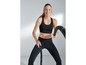 Eine Frau in einem schwarzen Sport-BH und Leggings trainiert mit einem Seil.
