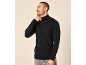 Mann in einem schwarzen Rollkragenpullover und einer grauen Hose.