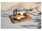 Käsebrett mit Messern, Käse, Trauben und Feigen, daneben Olivenöl und ein Tuch.