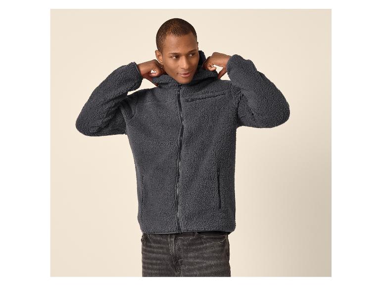 Mann in grauer Kapuzen-Fleecejacke und schwarzer Jeans.