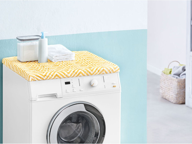 Eine weiße Waschmaschine mit einer gelben Abdeckung.