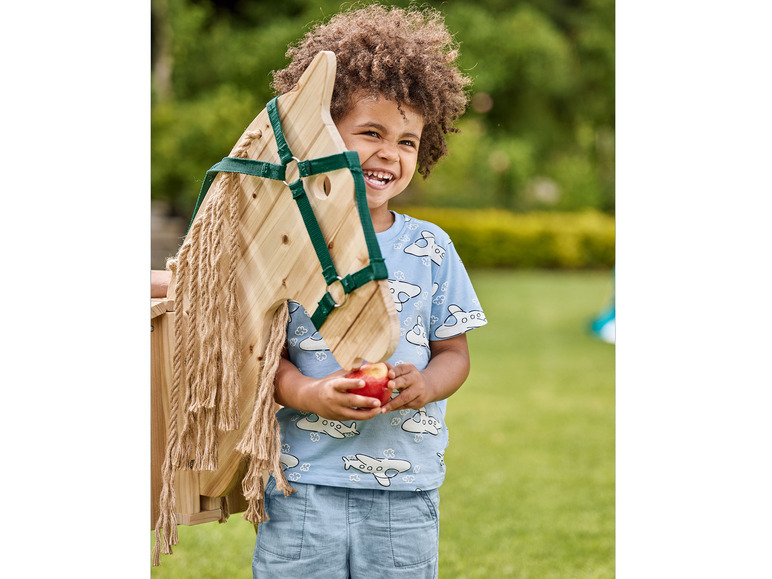 Ein Kind mit einem hölzernen Schaukelpferd und einem Apfel.