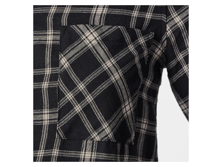 Eine Tasche auf einem schwarz-beige karierten Hemd.