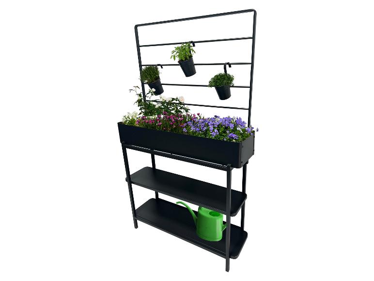 Schwarzes vertikales Hochbeet mit bunten Blumen und Kräutern, mit einer grünen Gießkanne auf dem unteren Regal.