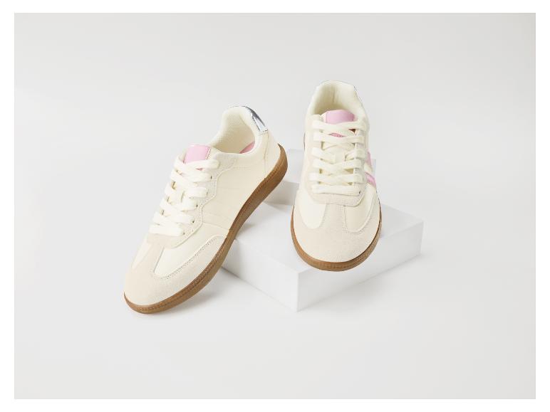 Beige Sneaker mit rosa Details und brauner Gummisohle auf einem weißen Block.