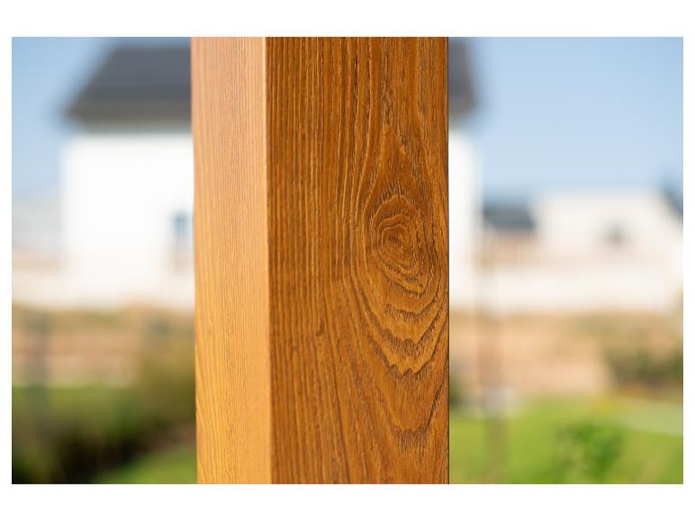 Holzbalken mit Holzmaserung, vor verschwommenem Hintergrund von Haus und Garten.