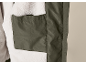 Innenseite einer grünen Jacke mit weichem, weißem Futter und einer Innentasche.