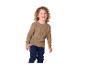 Kind in braunem Pullover und dunkelblauer Hose lächelt.
