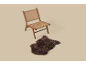 Holzstuhl mit geflochtener Sitzfläche und Rückenlehne, neben einem braunen Kunstfellteppich.