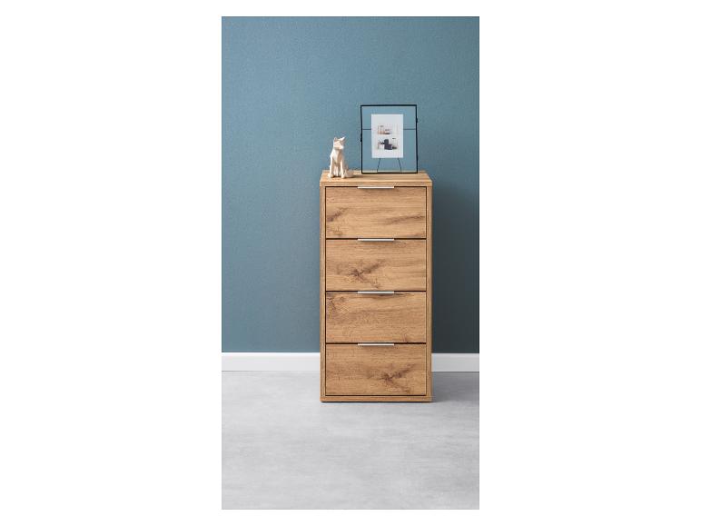 Eine Kommode aus Holz mit vier Schubladen vor einer blauen Wand.