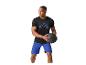 Mann in schwarzem T-Shirt und blauen Shorts hält einen schwarzen Medizinball.