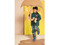 Kleiner Junge in dunkelgrüner Regenjacke und Regenhose mit Superheldenmuster, hält eine Regenschirm-Requisite.