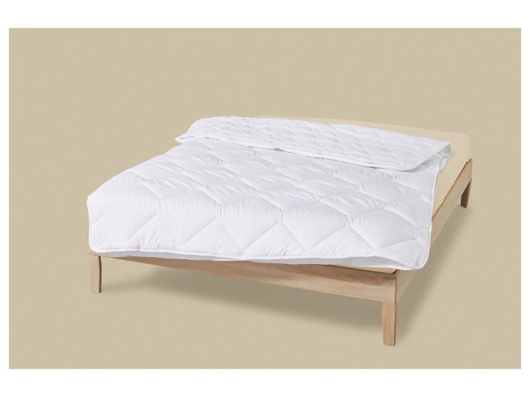 Weiße Steppdecke auf einem Holzrahmenbett mit beigem Laken