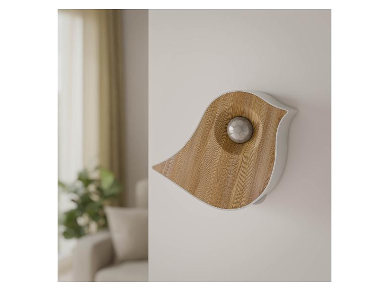 Wandgerät in Vogelform aus hellem Holz und Weiß, mit einer Kugel in der Mitte.