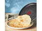 Bratpfanne mit Crêpes auf einem weißen Teller auf einem Holztisch.
