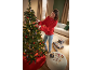 Frau schmückt Weihnachtsbaum mit Ornamenten, daneben Geschenke und Verpackungsmaterial.