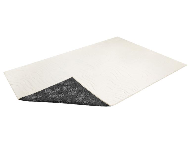 Cremefarbene Badematte mit Wellenmuster und dunkelgrauer rutschfester Unterseite mit Blumenmotiv.