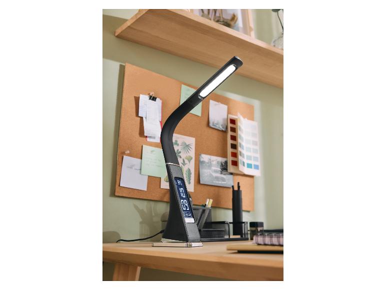 Schwarze LED-Schreibtischlampe mit Digitalanzeige auf einem Holzschreibtisch mit Korktafel.