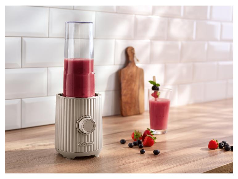 SilverCrest Mixer mit rotem Smoothie, Früchten und einem Glas auf einer Holztheke.