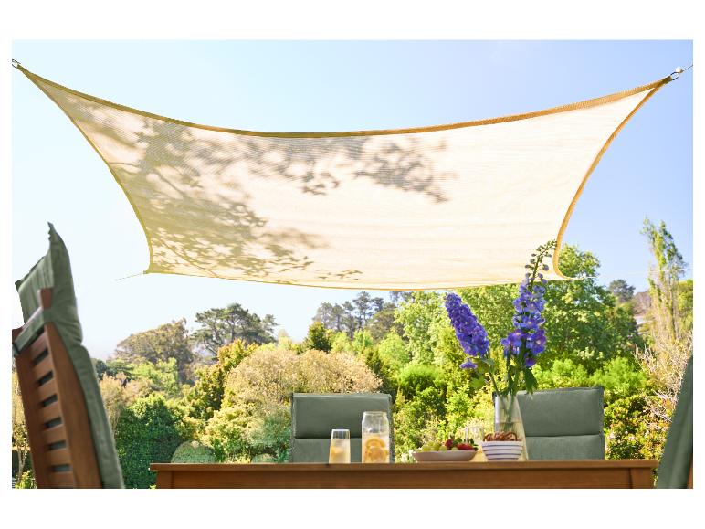 Beiges Sonnensegel über einem Holztisch im Garten mit Getränken und Snacks.