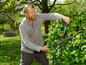 Ein Mann schneidet eine Hecke mit einer Fiskars Heckenschere.