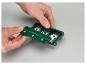 Hände halten einen grünen Kabelabisolierer mit Metallklingen