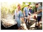 Frau grillt Fleisch und Brot draußen mit Freunden und einem Hund.