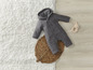 Ein grauer Baby-Overall mit Kapuze und ein Hasenrassel