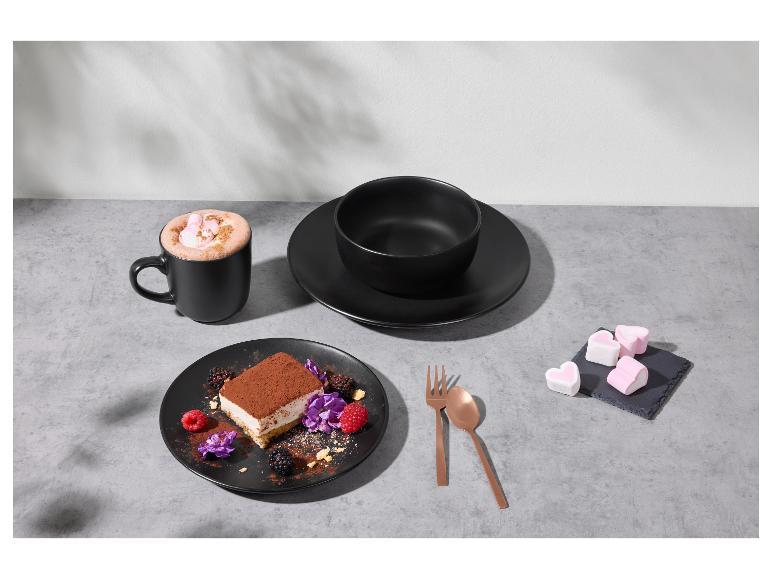 Schwarzes Geschirr mit Dessert, heißem Kakao und Marshmallows auf grauem Tisch.