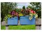 Blaue Blumenkästen mit bunten Blumen auf einer Holzbank im Garten.
