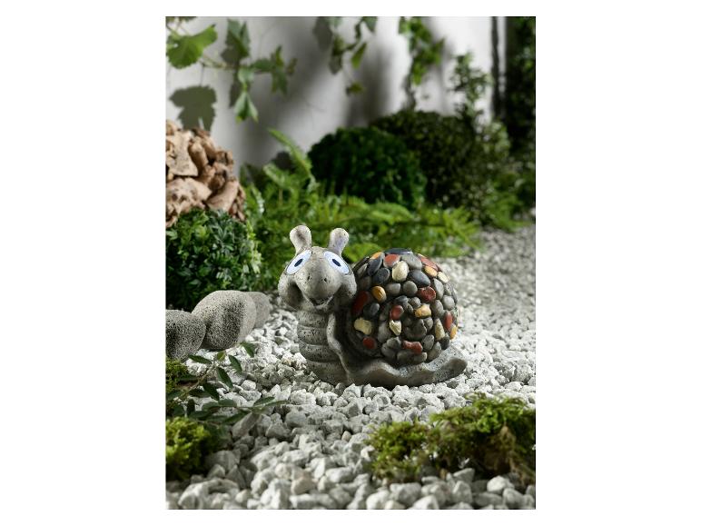 Eine süße Stein-Schneckenfigur mit großen Augen im Garten.