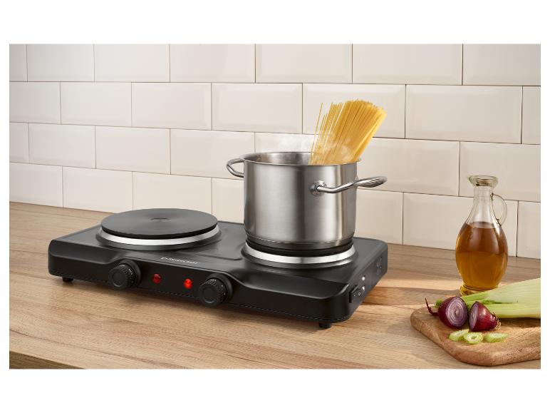 Tragbare Elektrokochplatte mit einem Topf kochender Spaghetti, Öl und gehacktem Gemüse.