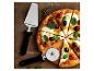 Pizza mit Tomaten, Oliven und Basilikum, mit Pizzaschneider und -heber auf Holzbrett.