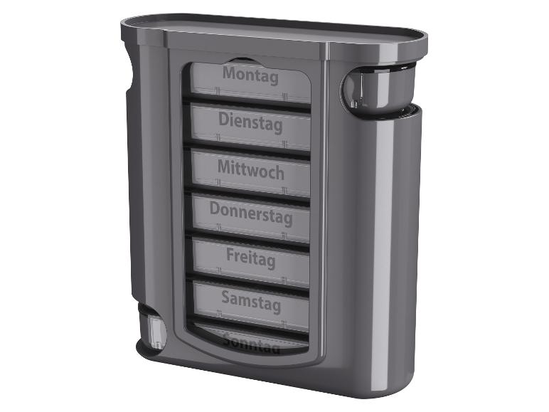 Grauer Pillendispenser mit sieben Fächern, beschriftet für jeden Wochentag auf German.
