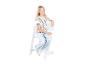 Blondes Mädchen in gestreiftem Shirt und Jeans sitzt auf einem weißen Hochstuhl