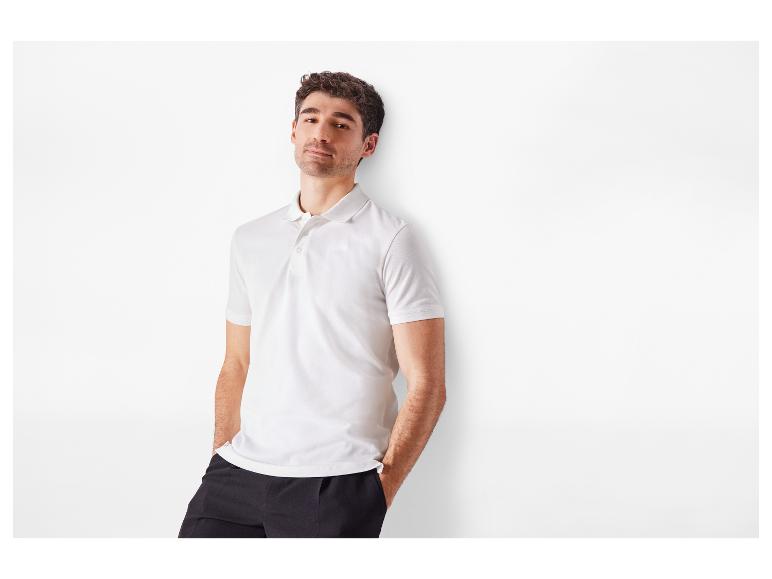 Ein Mann in einem weißen Polohemd und einer schwarzen Hose.